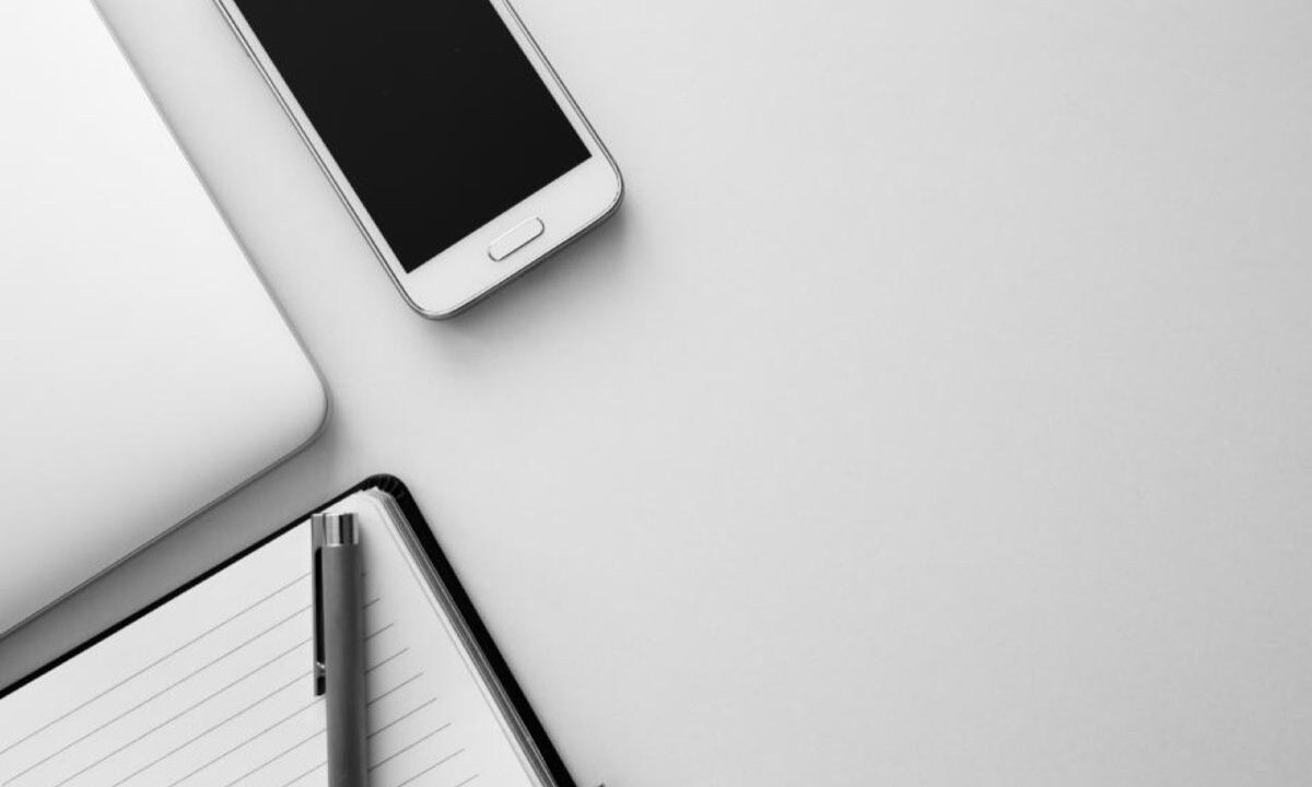 Smartphone tenu en main devant un ordinateur