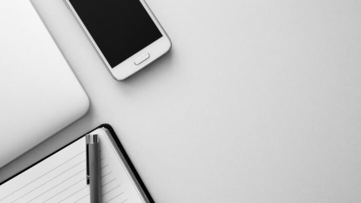 Smartphone tenu en main devant un ordinateur
